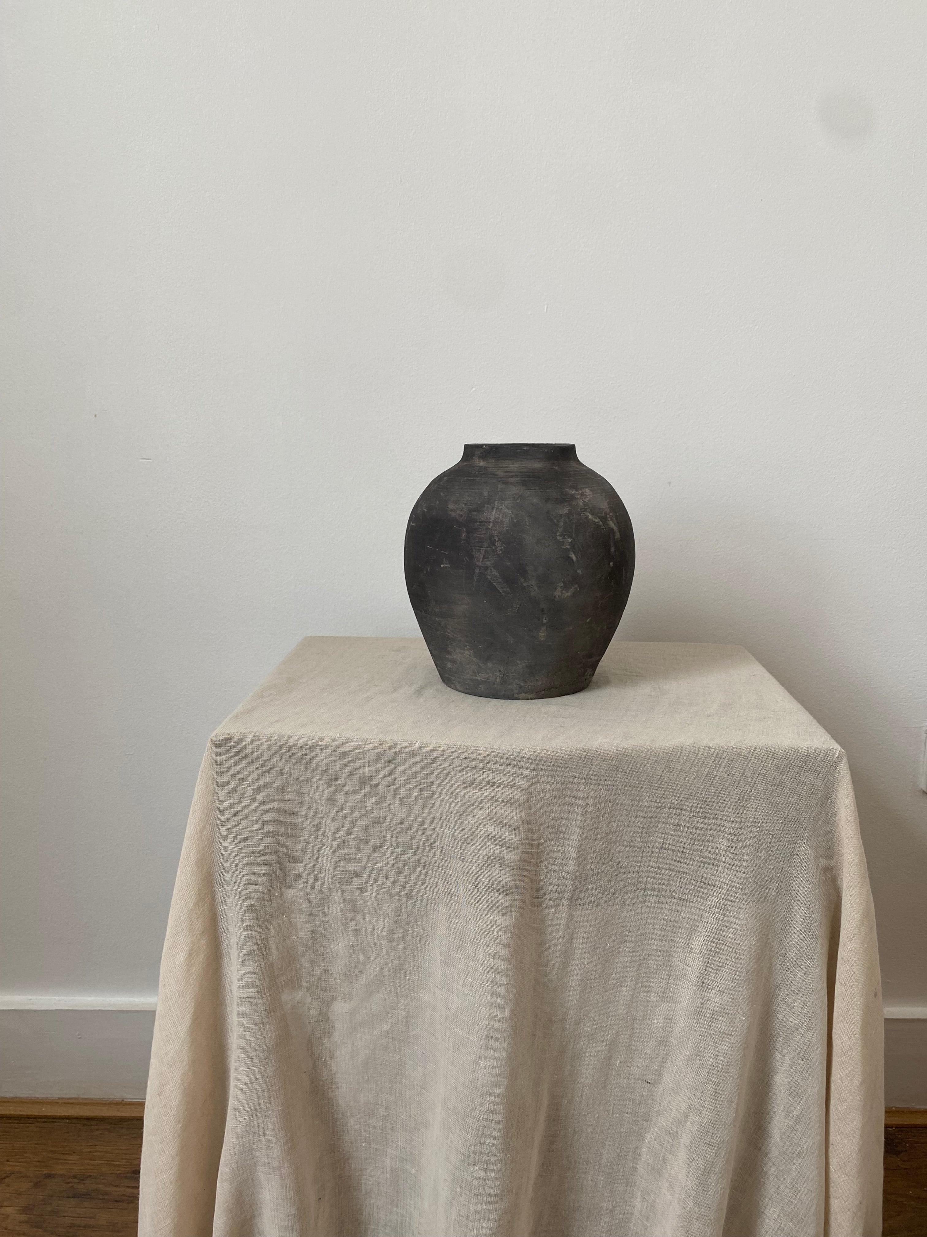 Black and grey antique clay pot on a linen cloth.