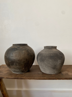 Two antique terracotta clay pots on a wooden shelf
