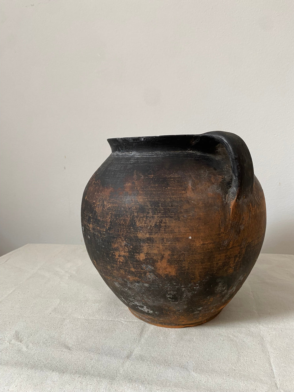 Backview of Two rustic black pots on a textured white surface