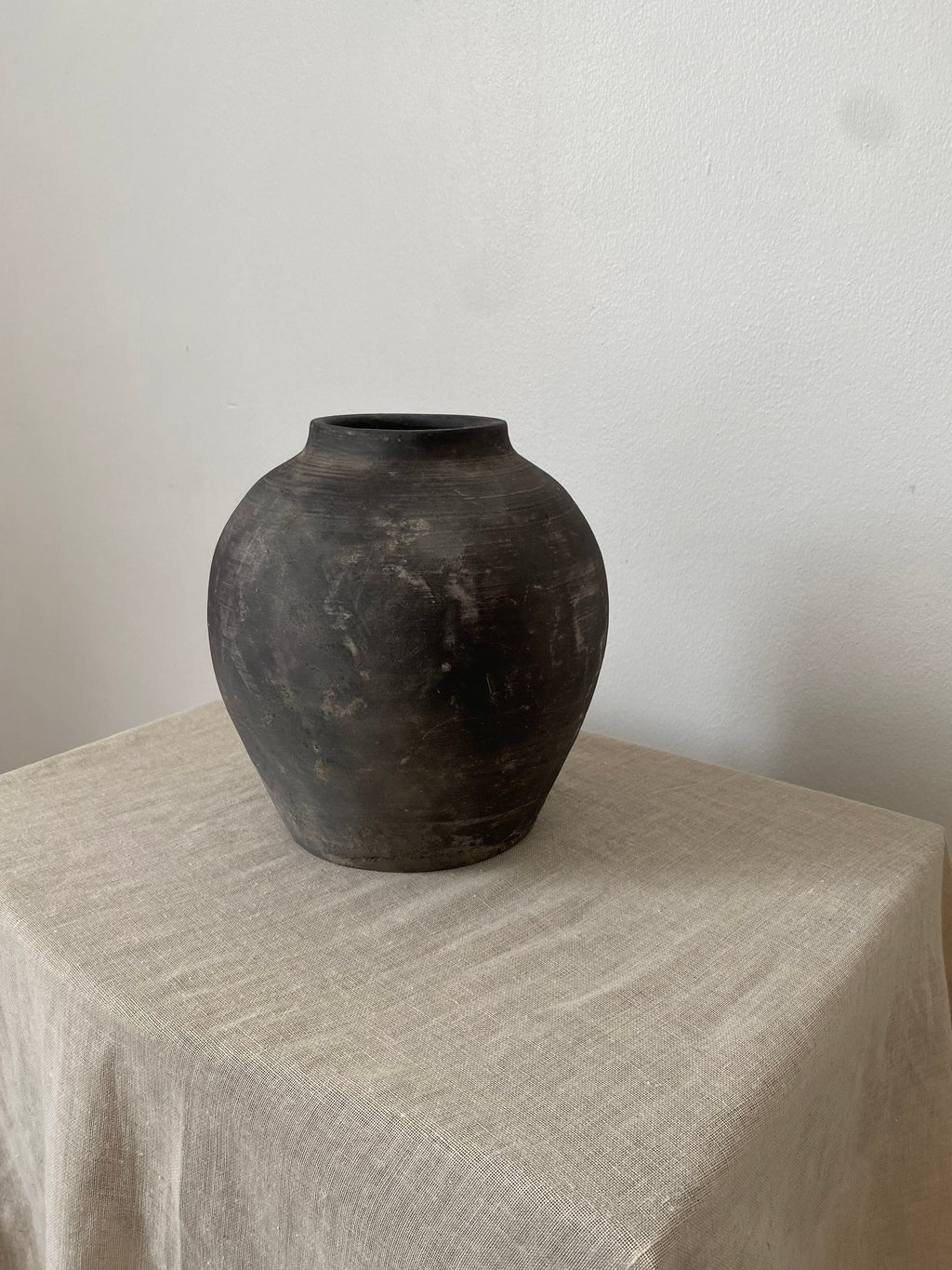 Black and grey antique clay pot on a linen cloth.