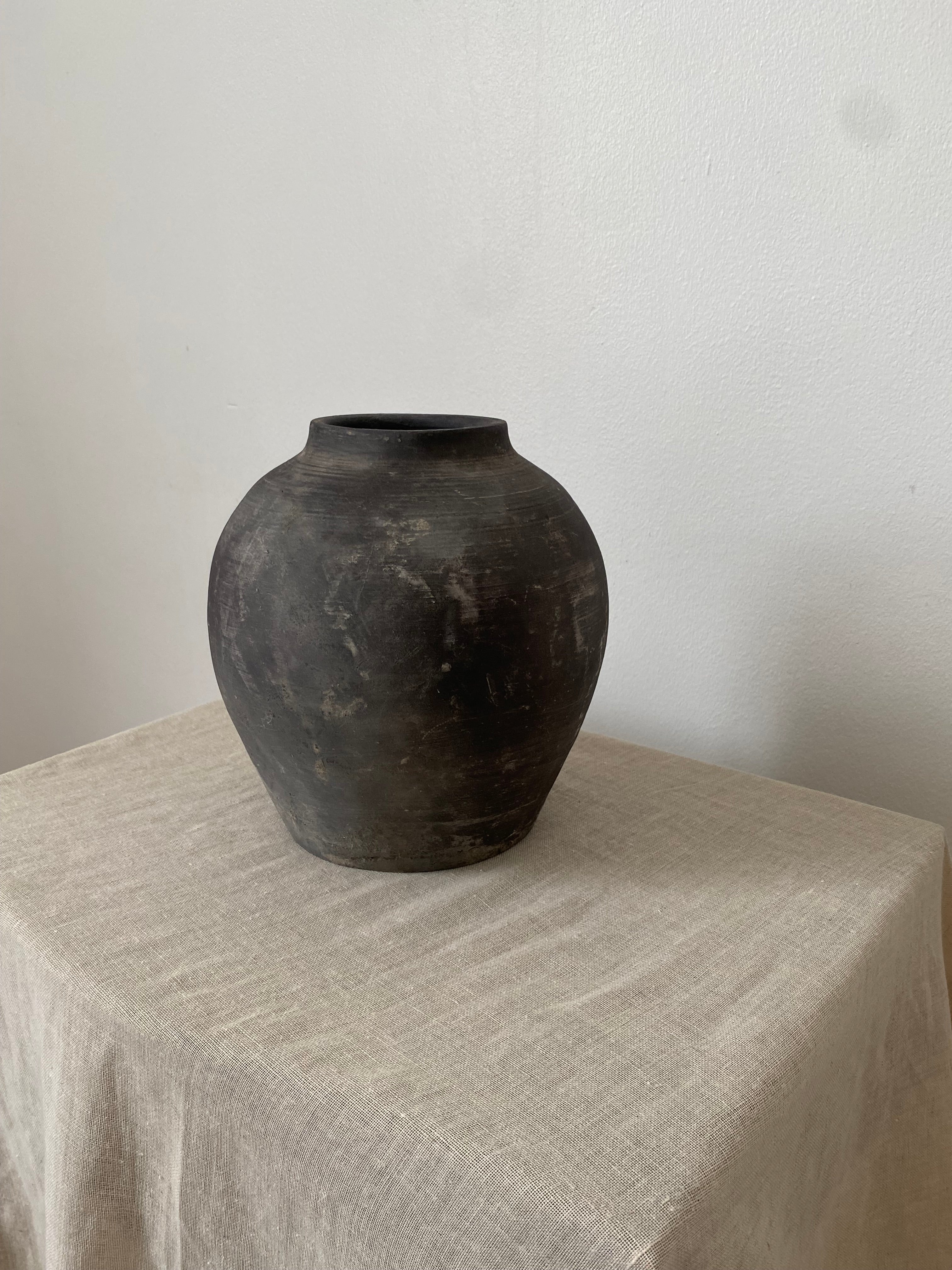 Black and grey antique clay pot on a linen cloth.