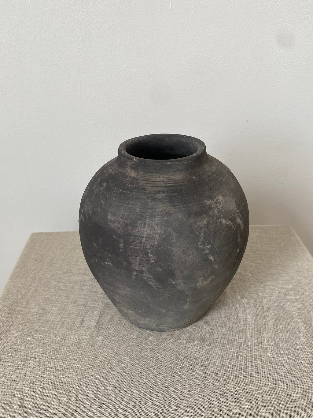 Black and grey antique clay pot on a linen cloth.