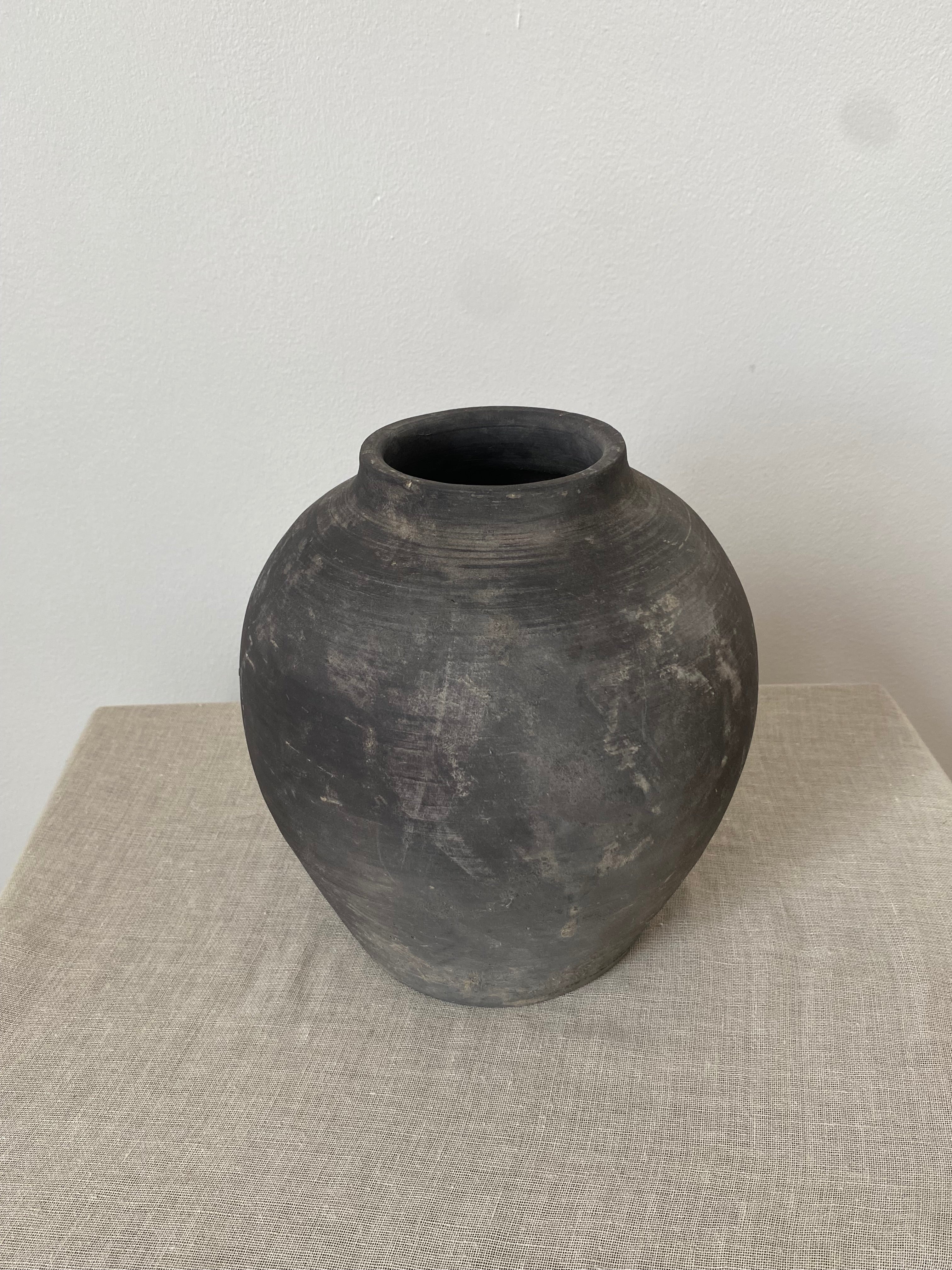 Black and grey antique clay pot on a linen cloth.