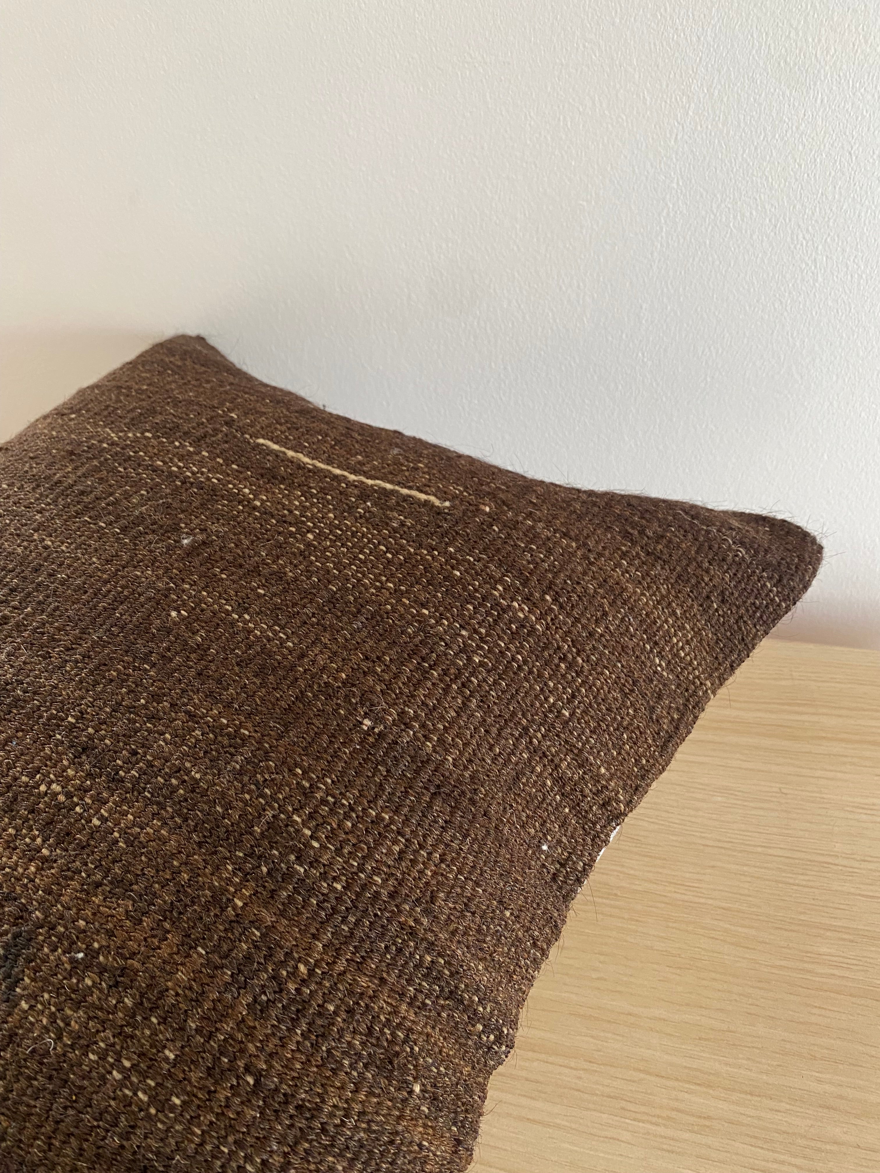 Close-up of a textured brown Turkish Pillow Cover on a light wooden surface.