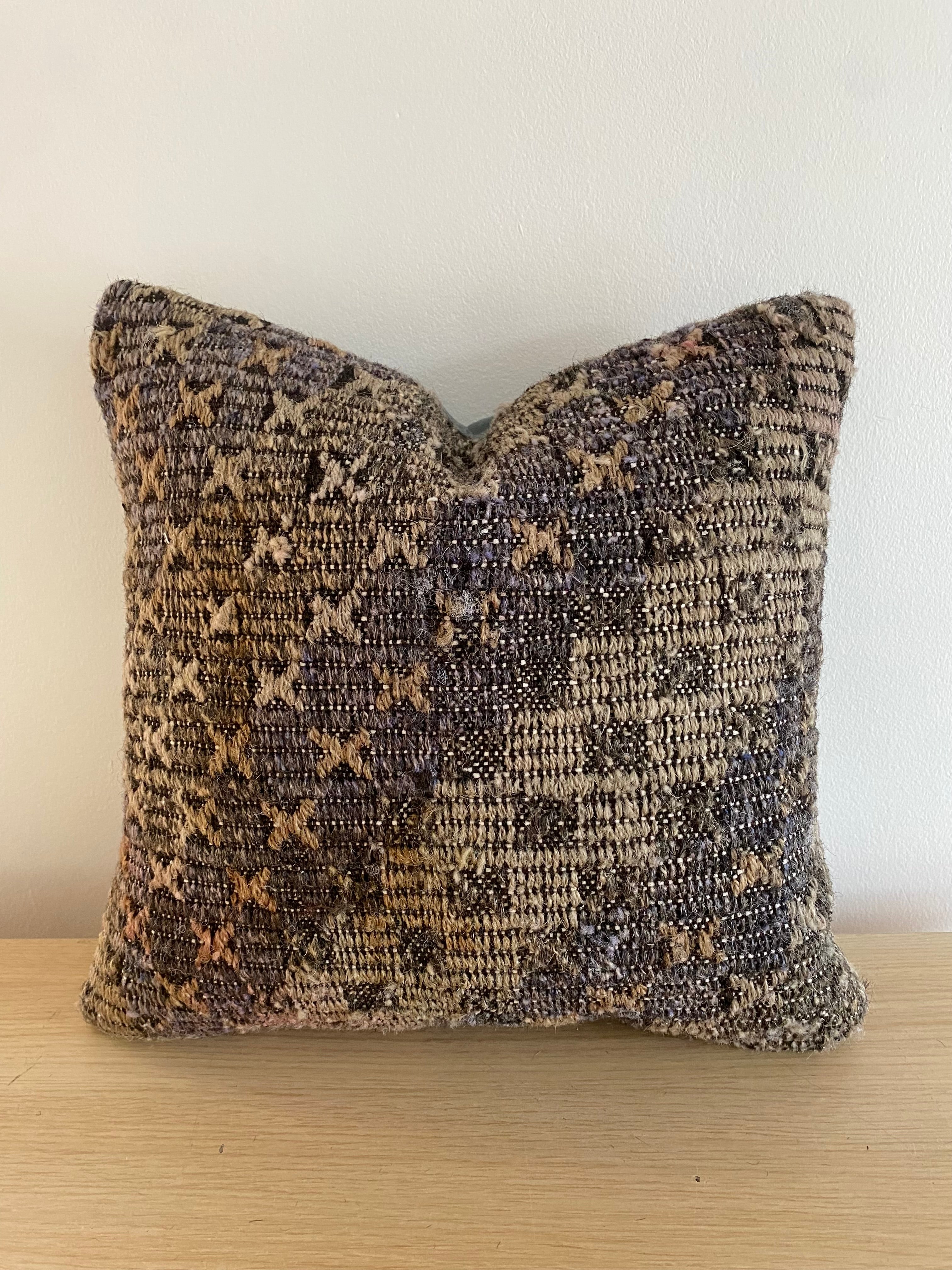 Textured Turkish Kilim Pillow Cover with a pattern on a wooden surface and white background