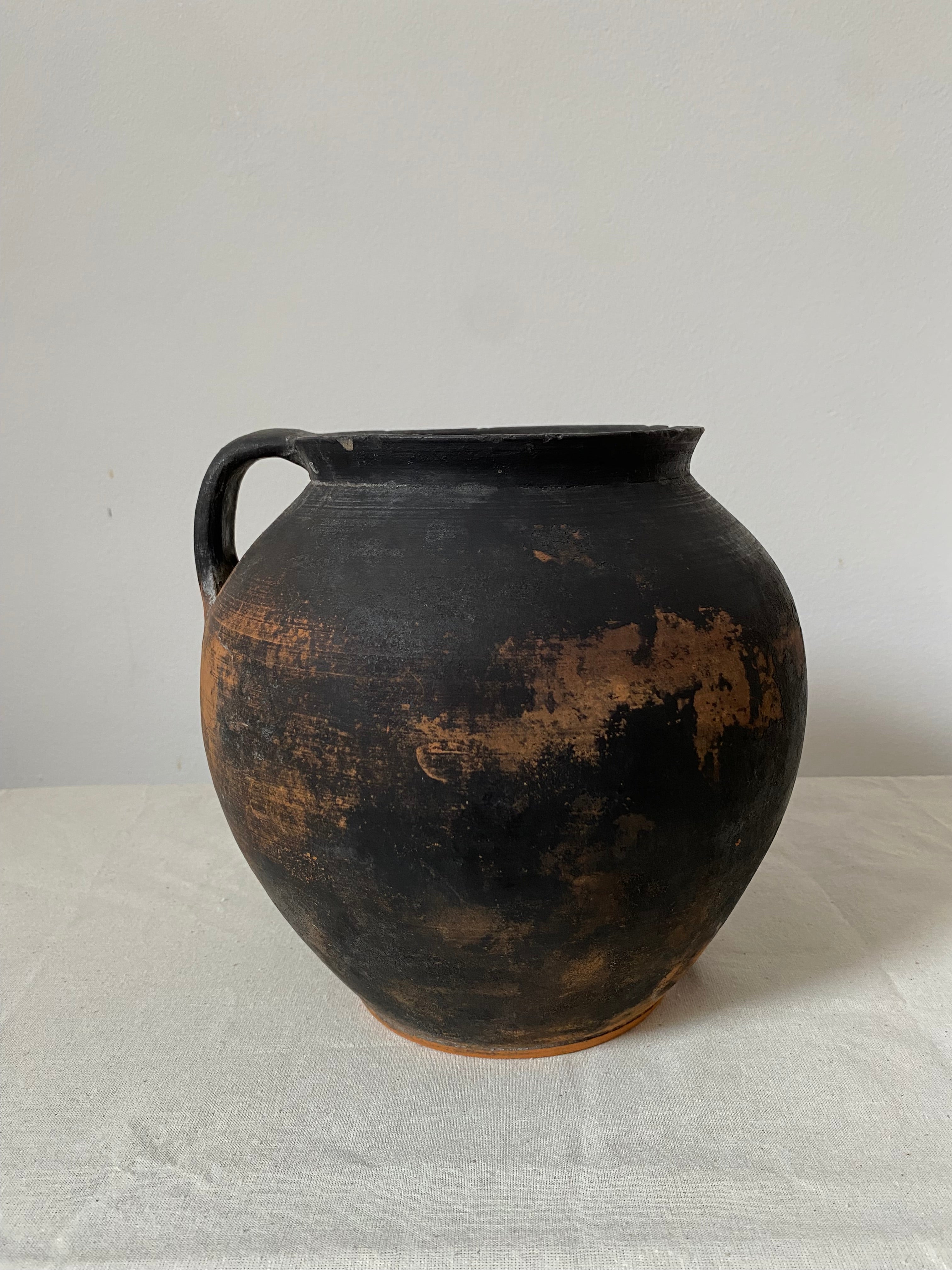 Side view Black terracotta pot with a textured surface on a light gray background