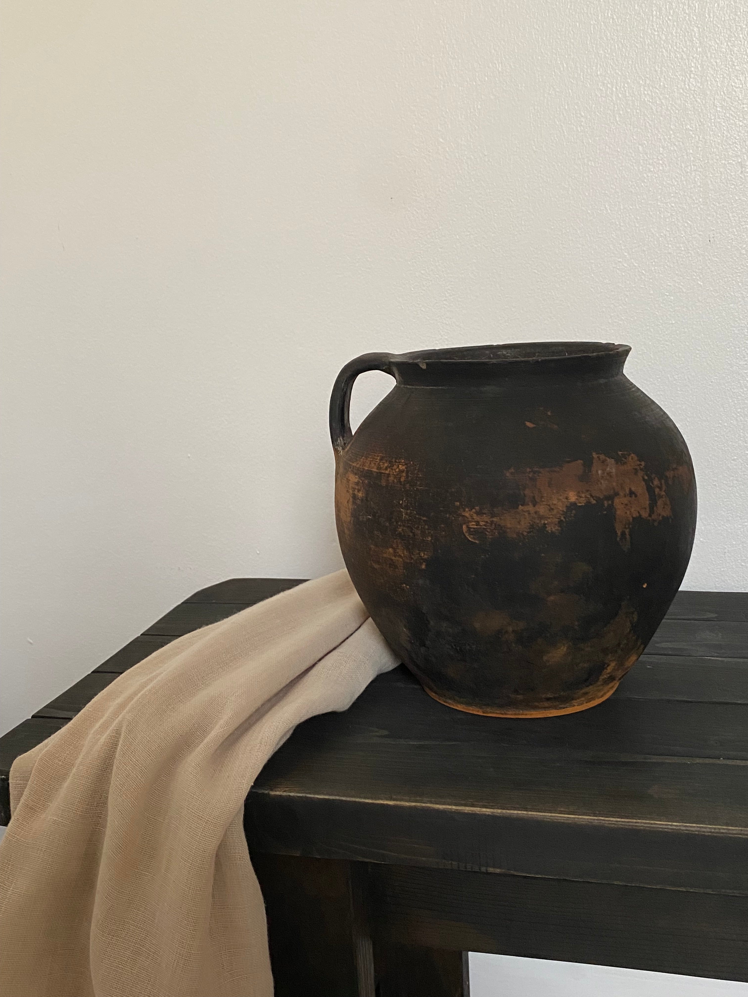 Black and brown antique terracotta clay pot on wooden bench