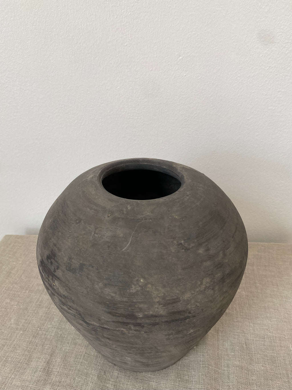 Black antique clay vessel on a light beige linen cloth