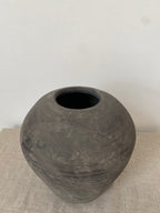 Black antique clay vessel on a light beige linen cloth