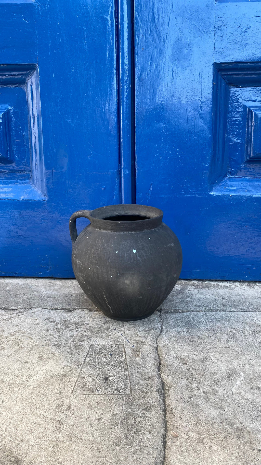 Black antique clay pot on a light grey background