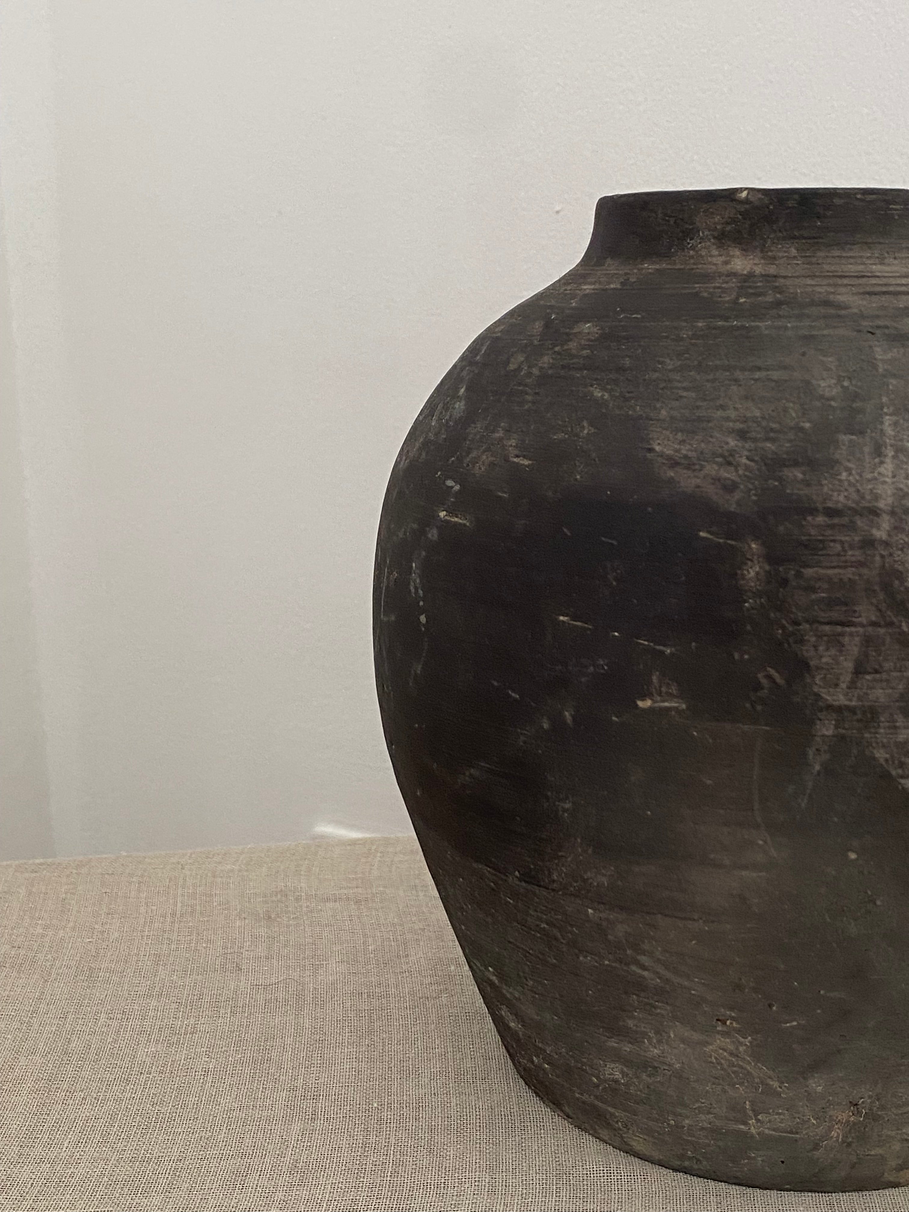 Close-up of a dark grey clay pot on a light linen  fabric