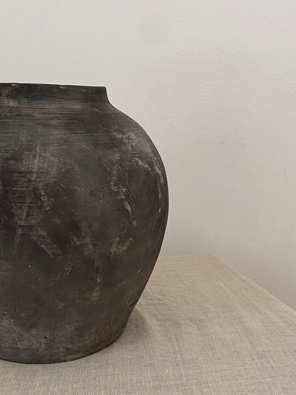 Black grey clay pot on a linen cloth.