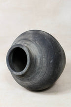 Black grey clay pot on a light beige background