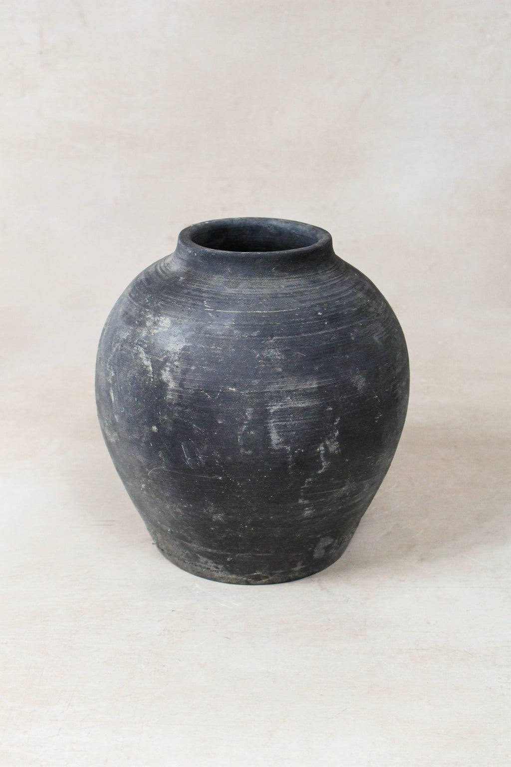 Black grey clay pot on a light beige background