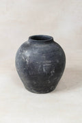 Black grey clay pot on a light beige background