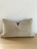 Turkish Kilim cushion cover textured beige pillow cover on a wooden surface with a light grey background