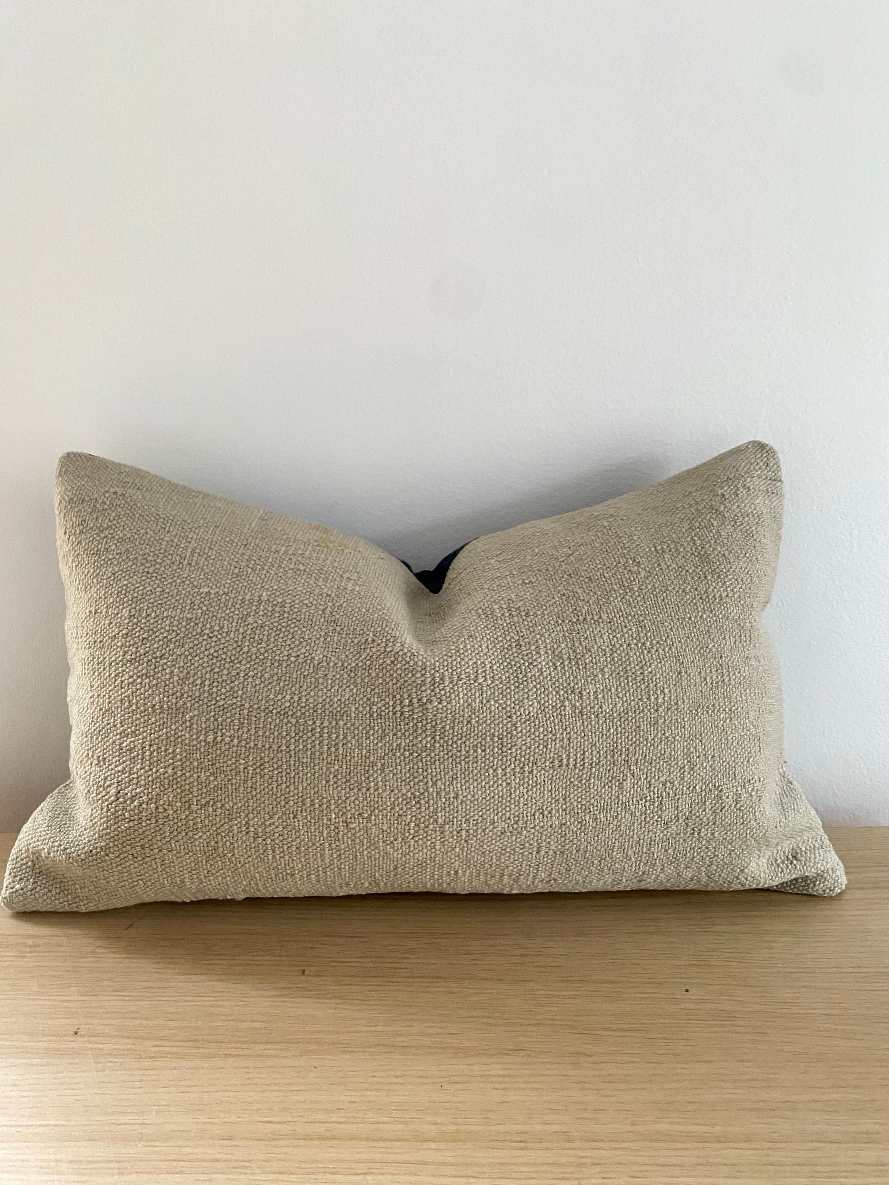 Turkish Kilim Textured beige pillow cover on a wooden surface with a light grey background