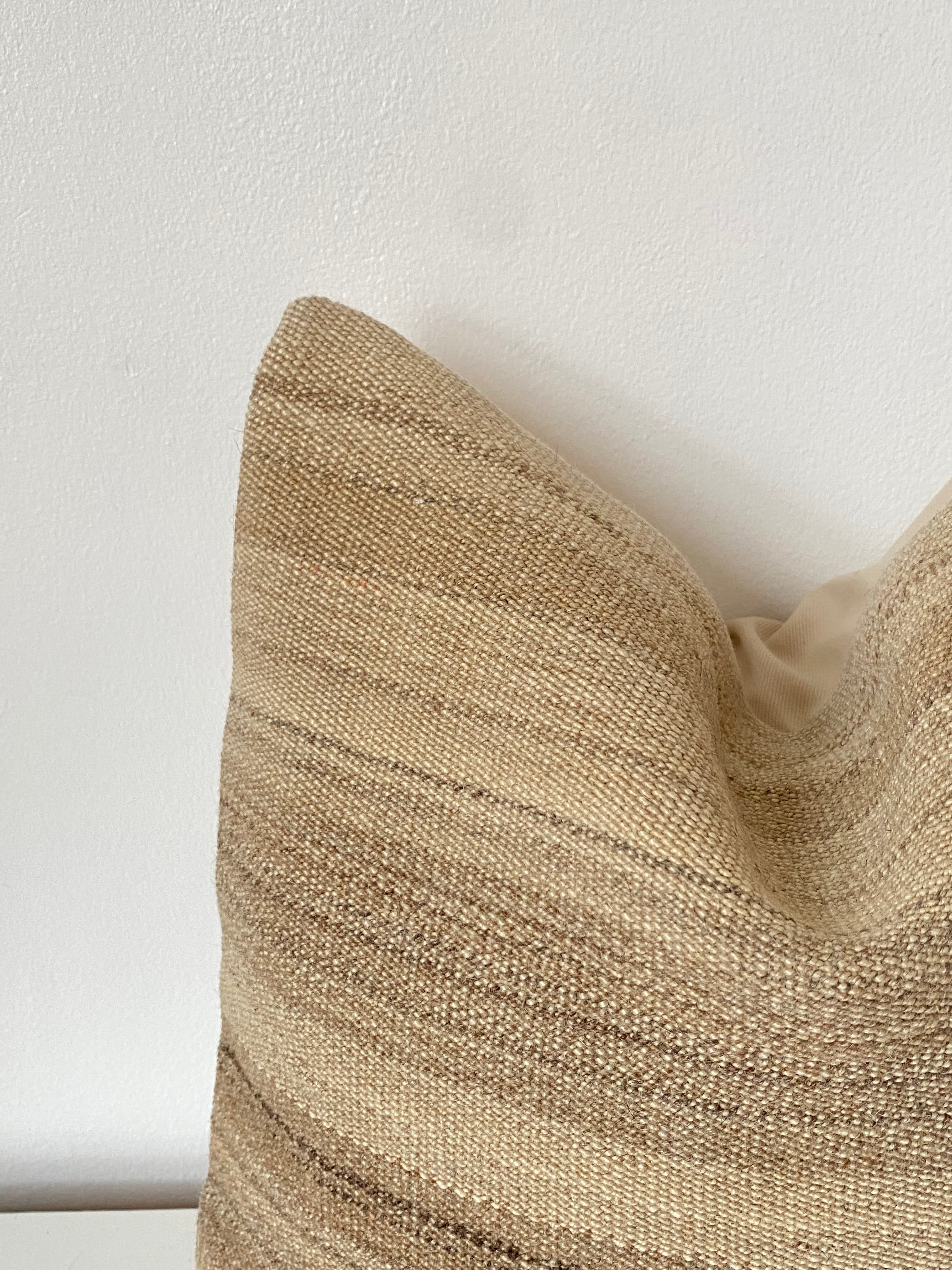 Close-up of a textured beige Turkish Kilim pillow cover on a white background
