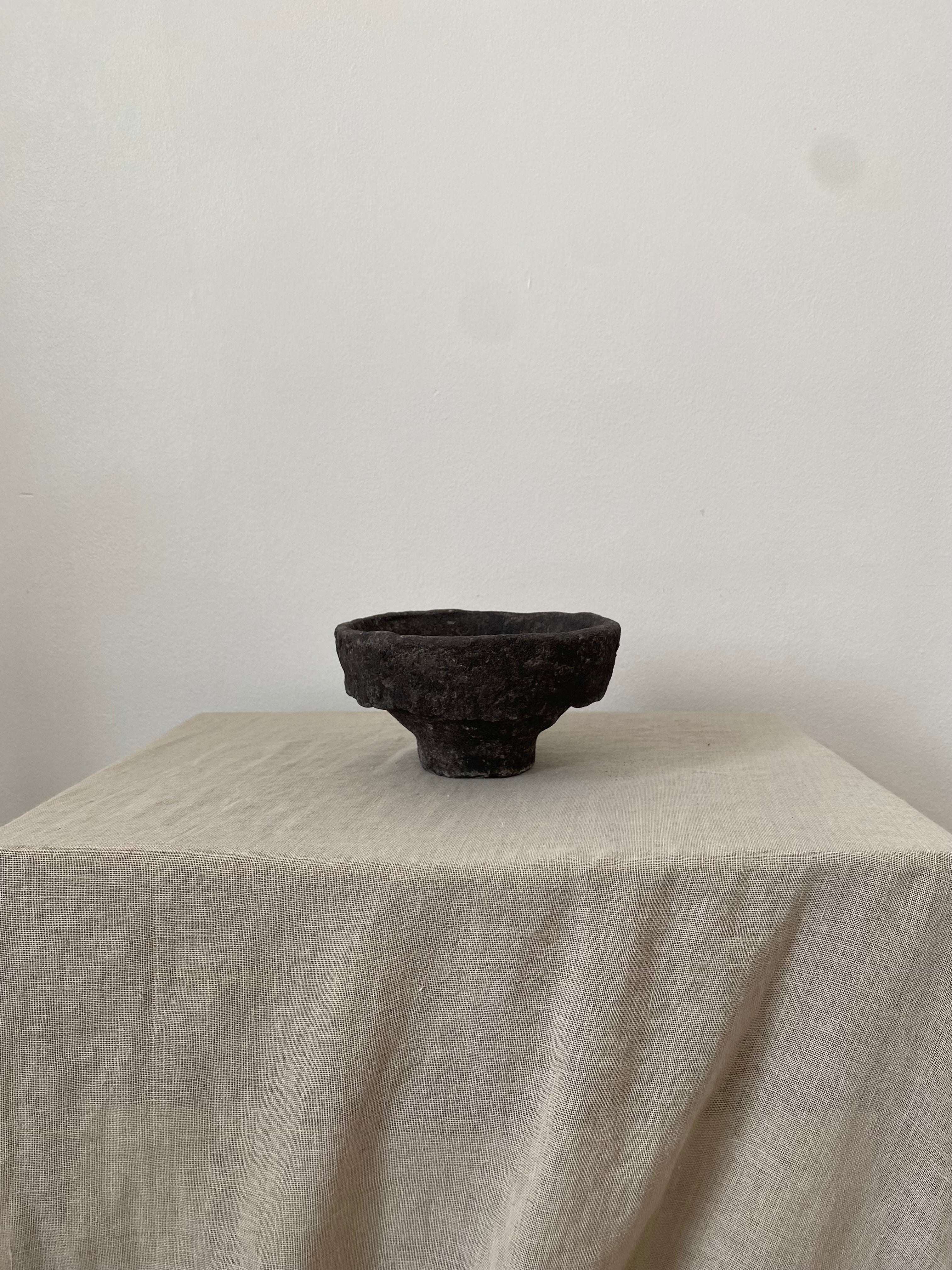 Black papiermache bowl on a beige tablecloth with a plain white background