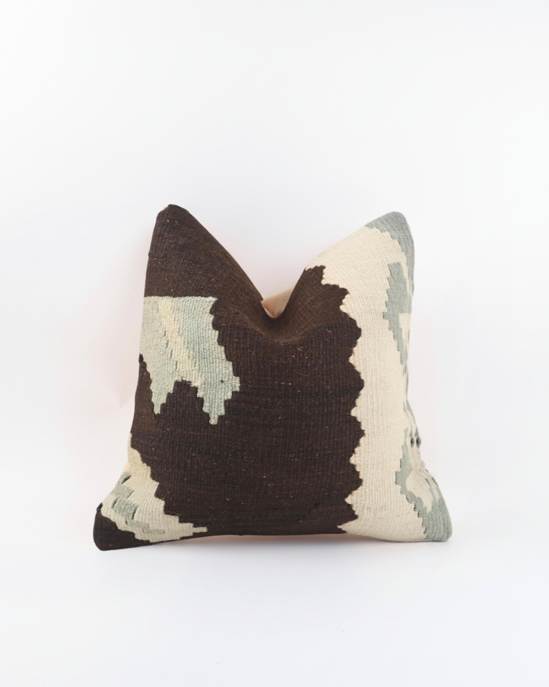 A square brown Turkish Kilim decorative throw pillow cover featuring a textured, woven kilim pattern in dark brown, cream, and sage green, set against a plain white background.