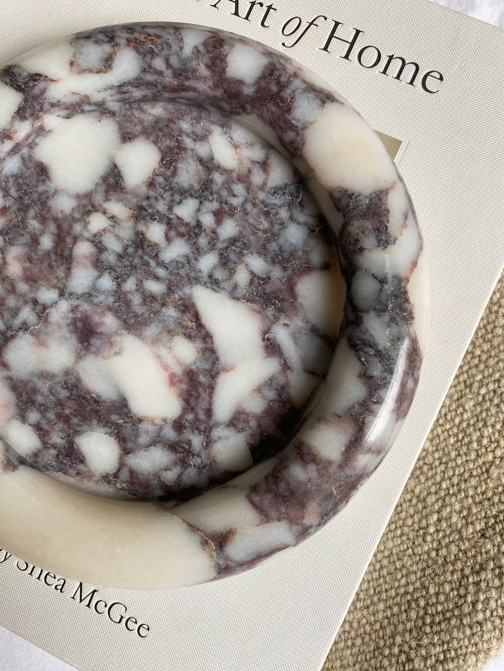 Round Calcutta Marble-patterned soap on a book titled 'The Art of Home' by Shea McGee.