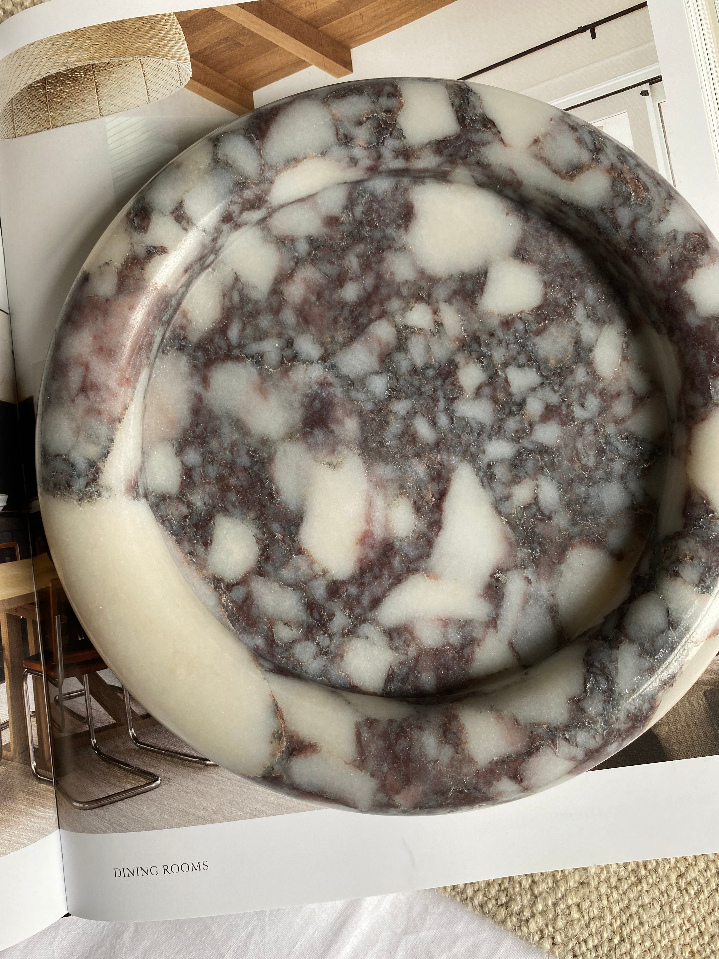 Round Calcutta Marble-patterned tray on a decorative book