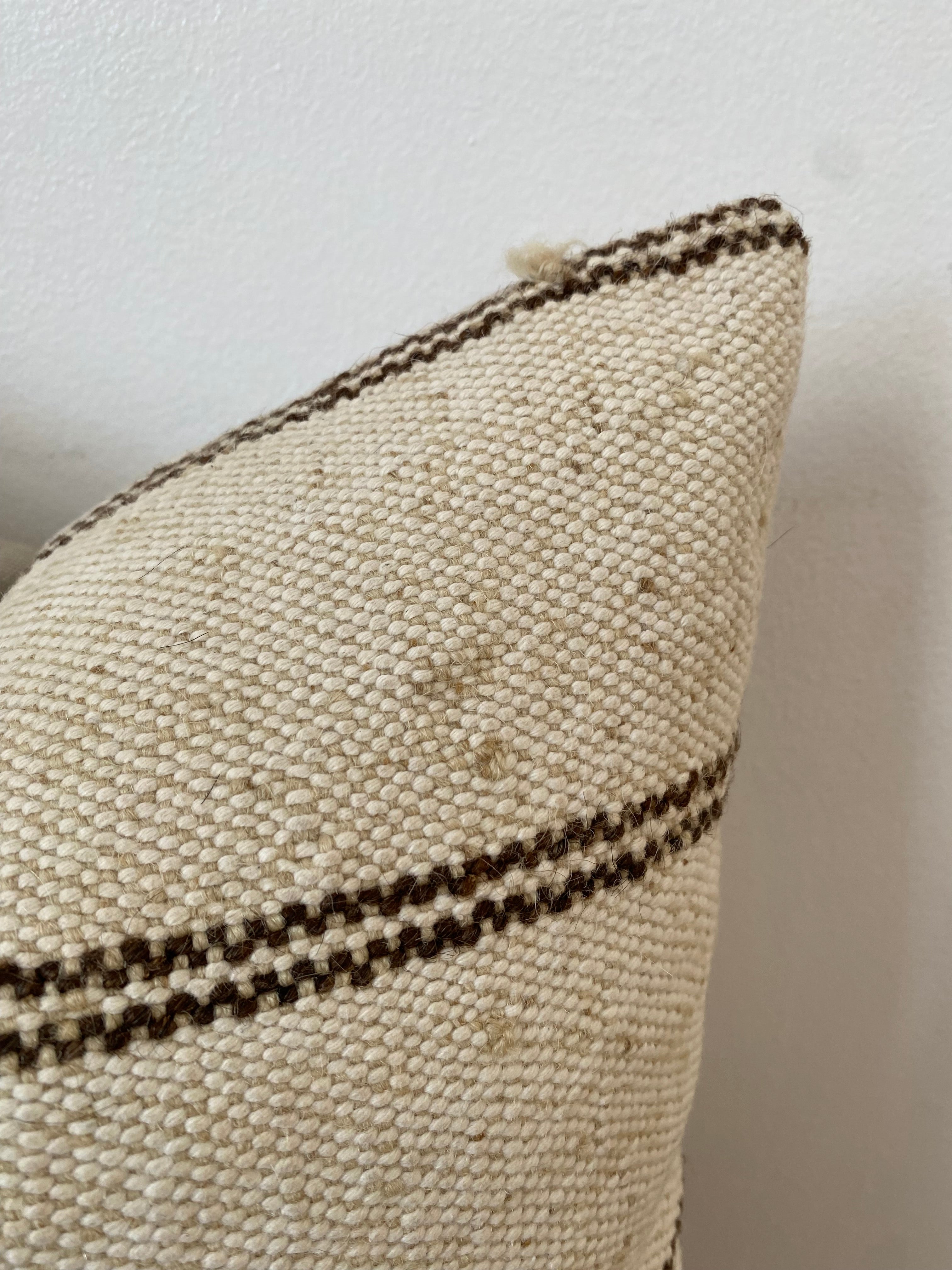 Textured cream pillow cover with a dark stripe on a light background