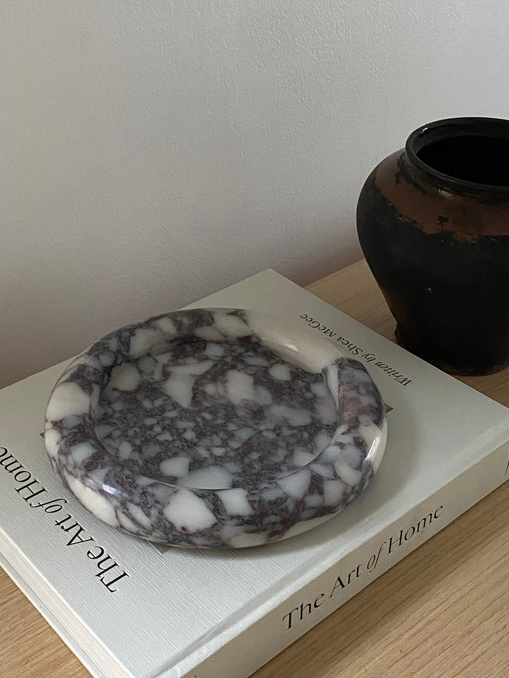 Calacatta Viola Marble round tray on a book titled 'The Art of Home'.