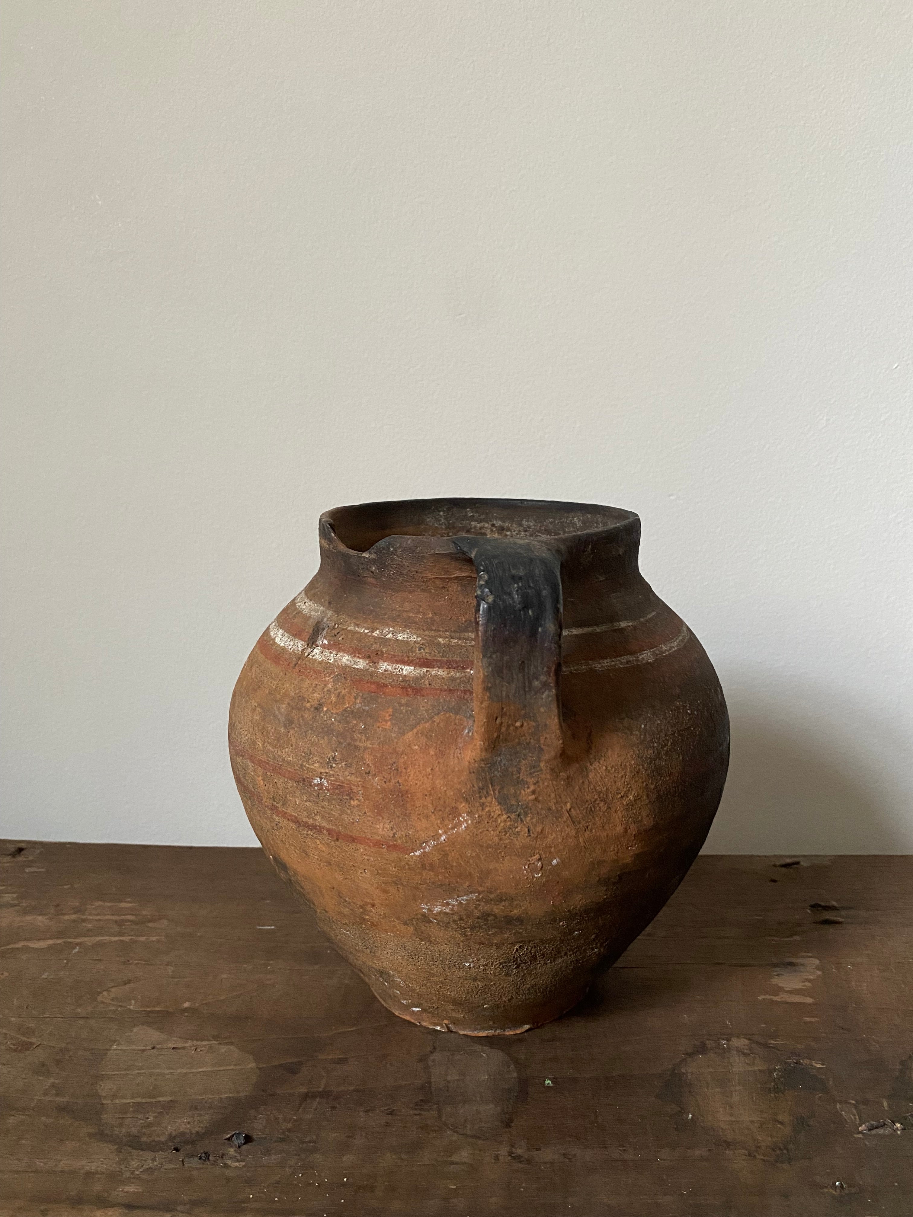 Brown vintag clay pot with a handle on a wooden surface