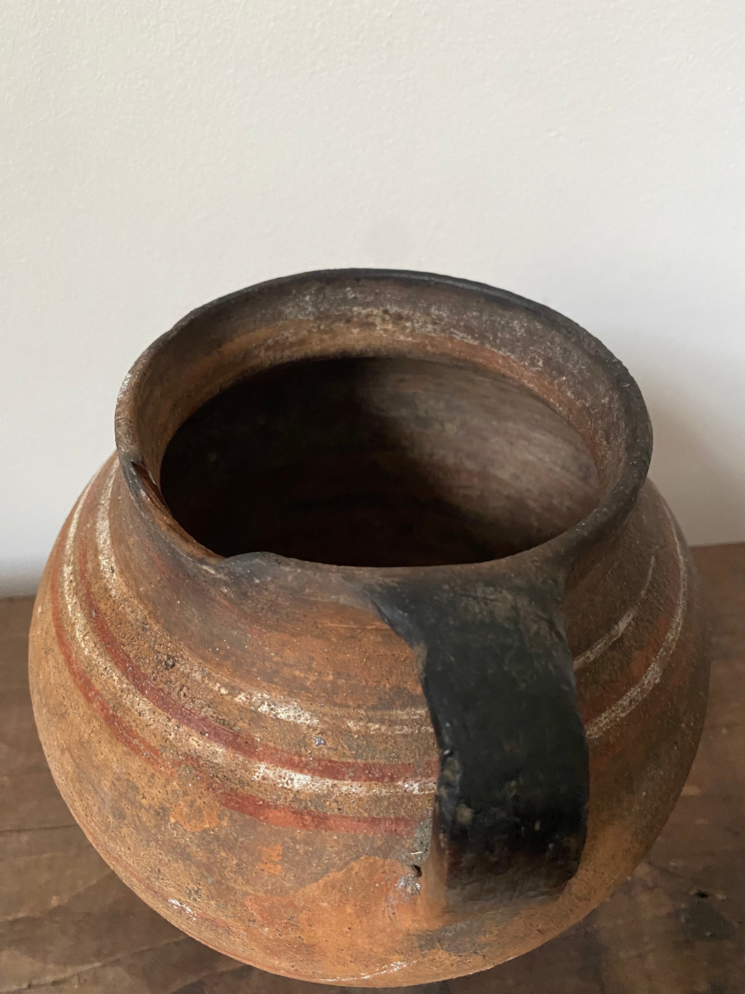 Close-up of a antique clay pot with a ribbed texture on a white background