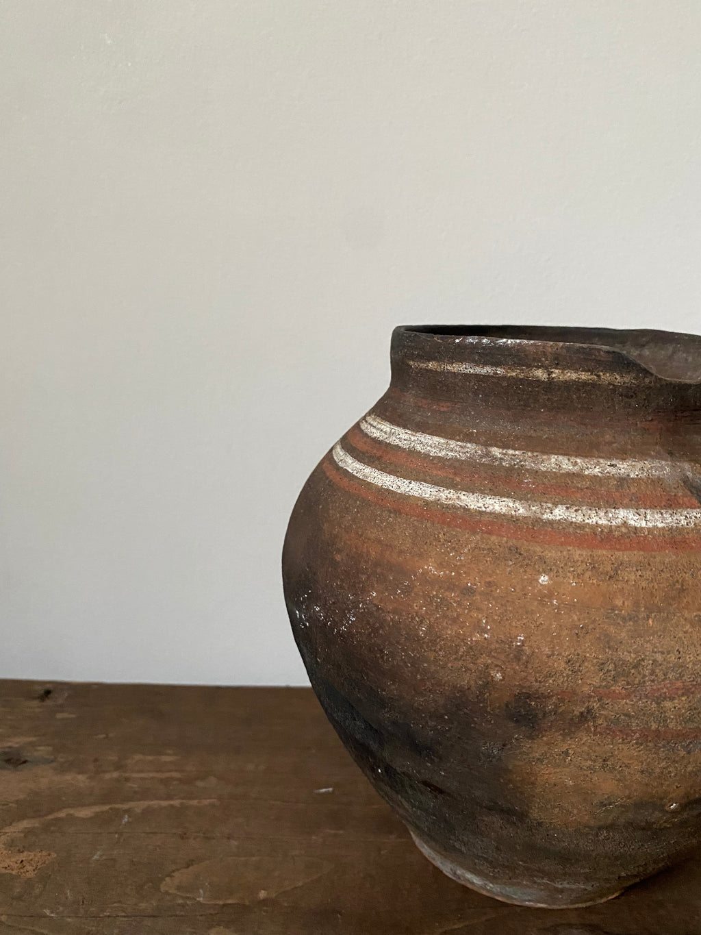 Close-up of a vintage clay pot with striped design on a white background