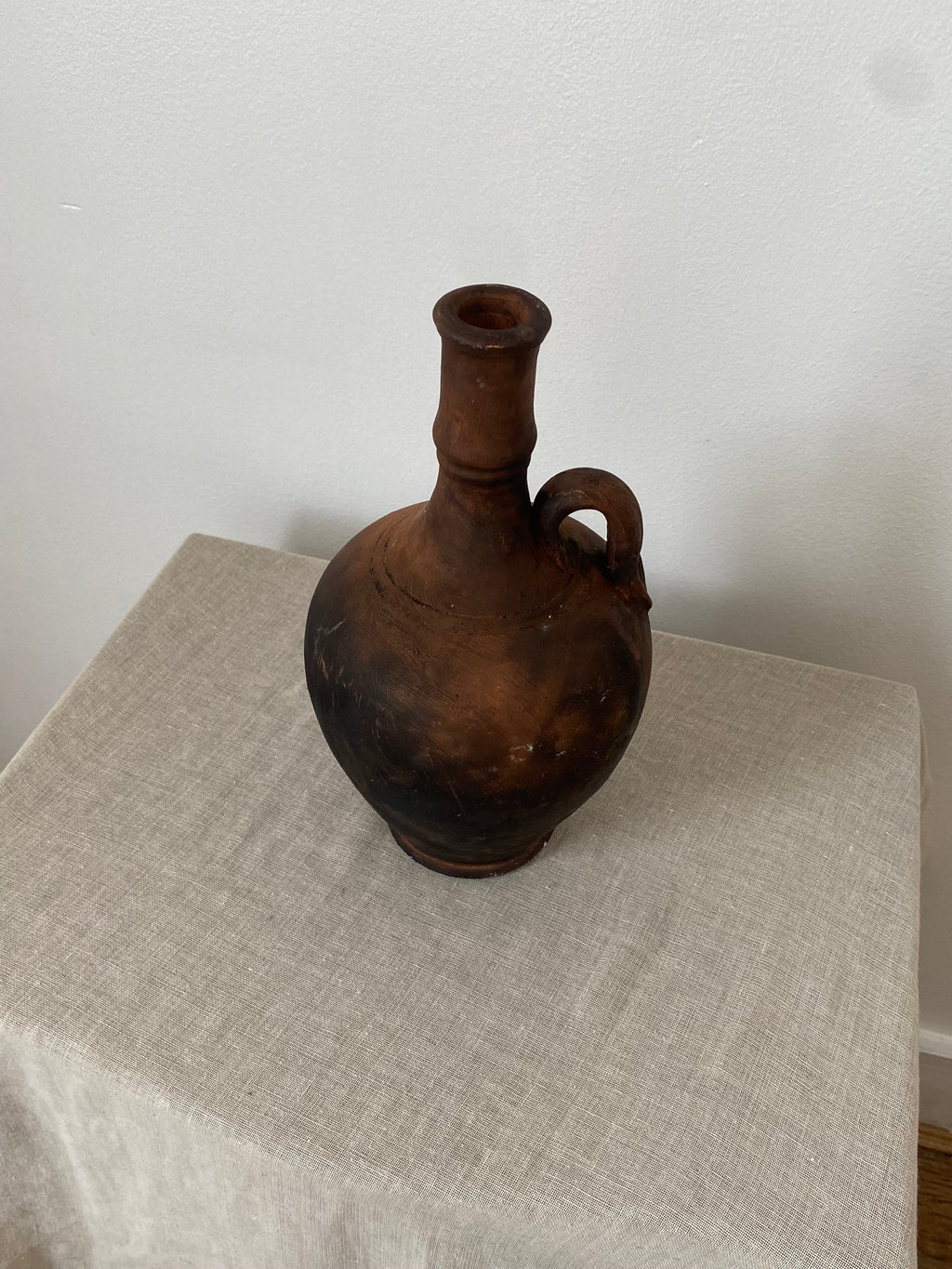 Vintage brown pitcher on a beige linen cloth
