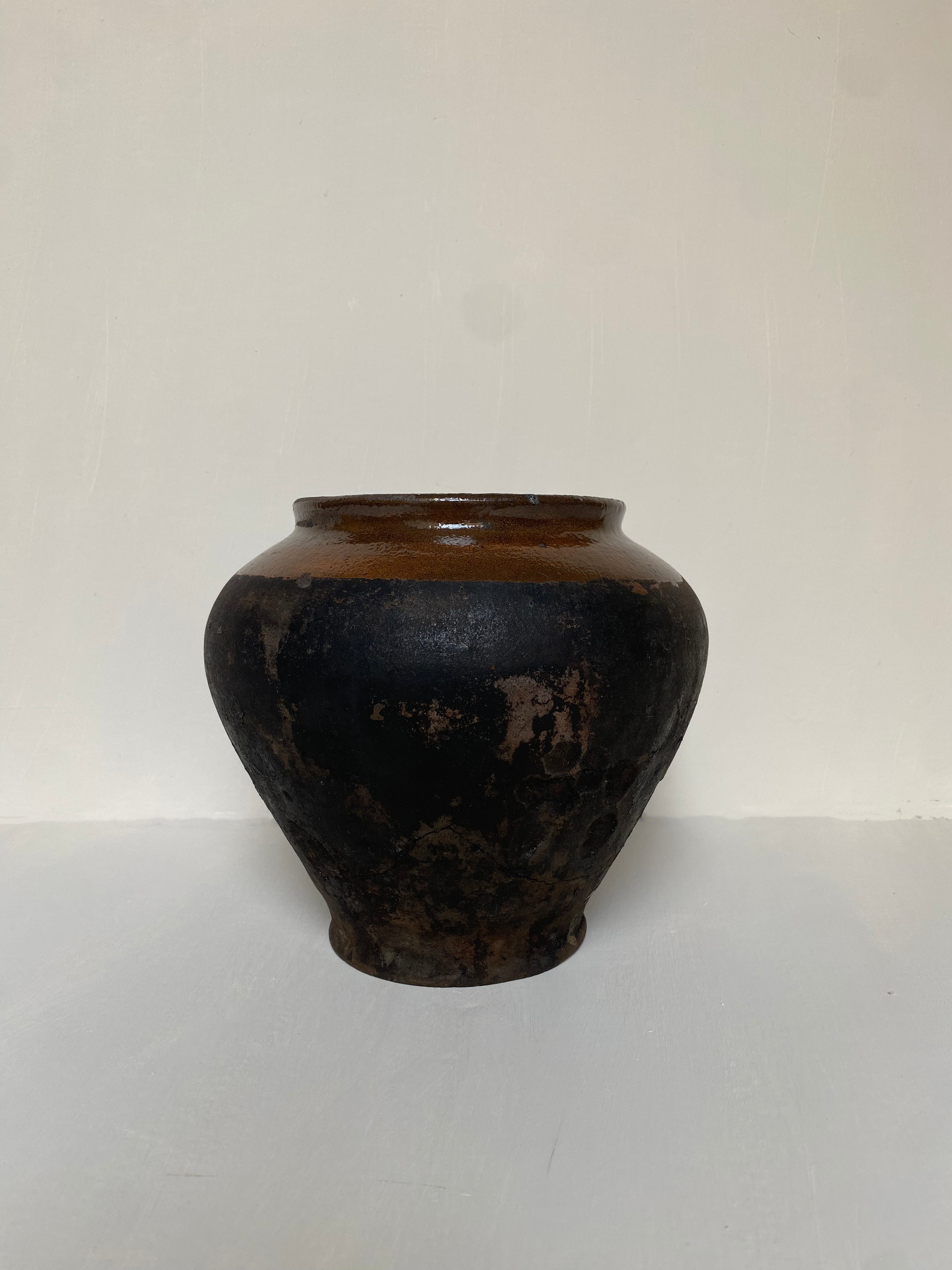 Black antique terracotta clay pot on a cream background 