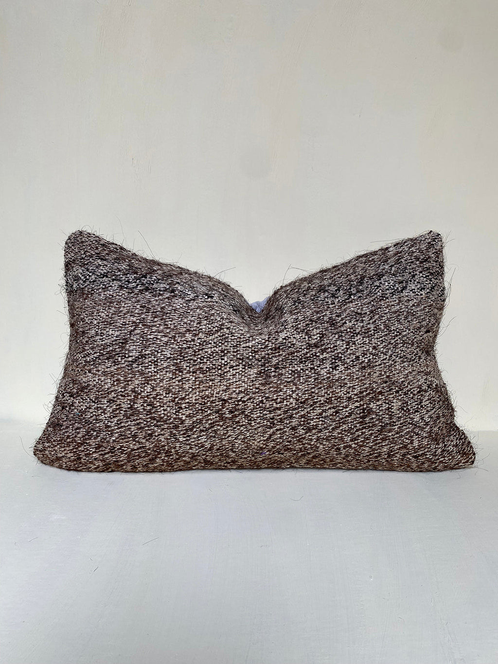 Handwoven brown kilim cushion with natural wool and goat hair blend, textured for rustic interiors. A vintage-style lumbar cushion for neutral home decor.
