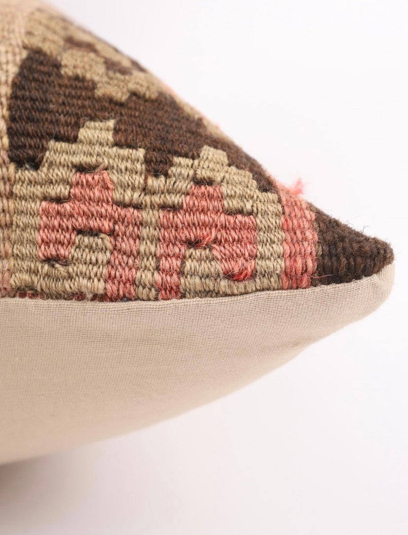 Close-up Turkish Kilim Pillow cover showing a geometric kilim pattern in brown, beige, and dusty pink, with a solid beige fabric bottom edge on a white background.
