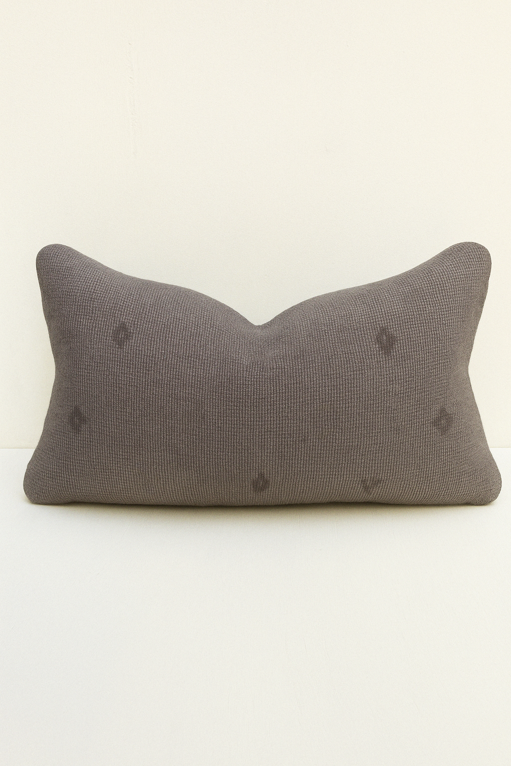 Dark beige Turkish kilim lumbar cushion made from vintage handwoven wool, perfect for rustic interiors and textured neutral decor.
