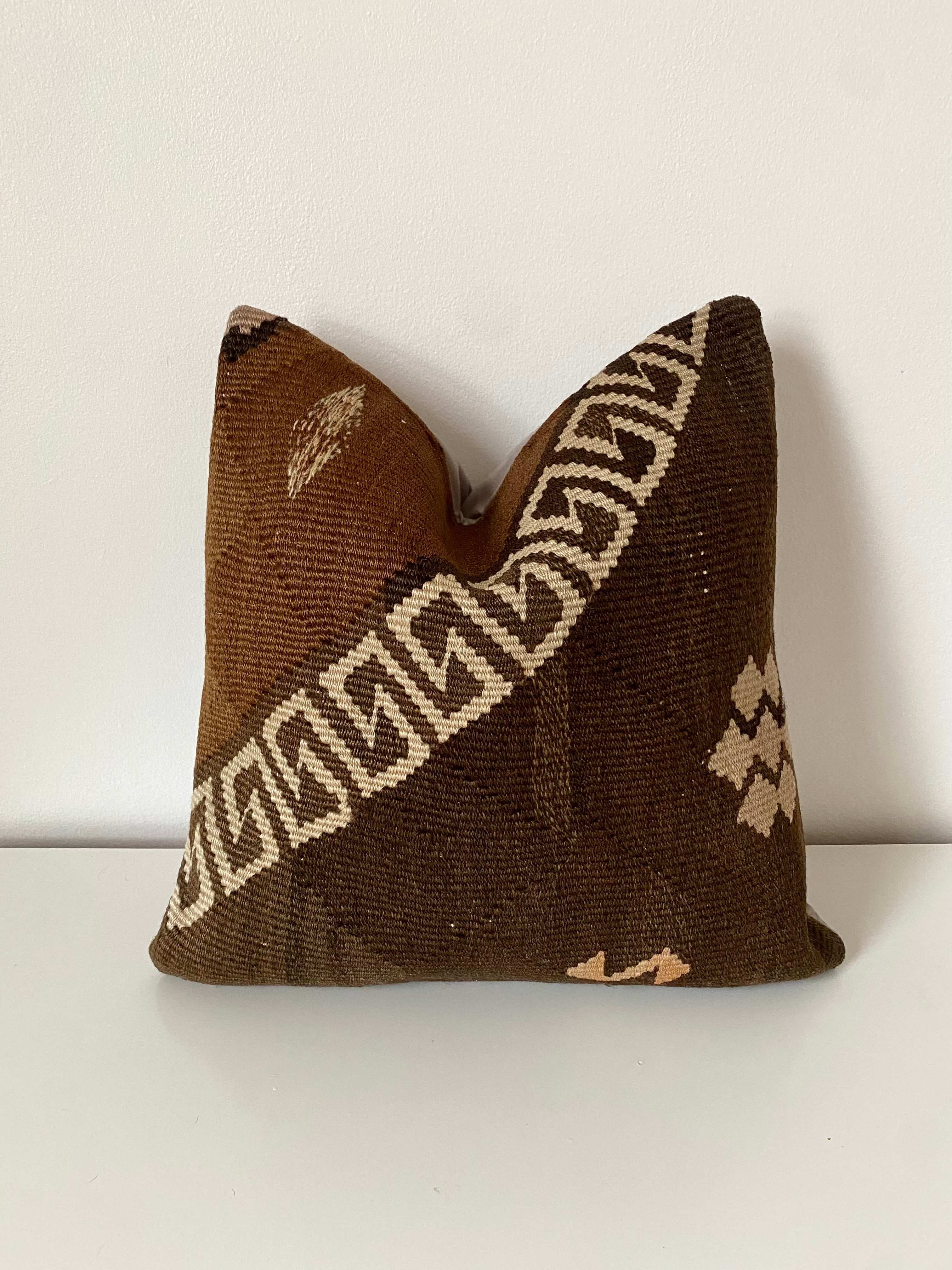 Brown Turkish Kilim pillow cover with geometric pattern on a white background