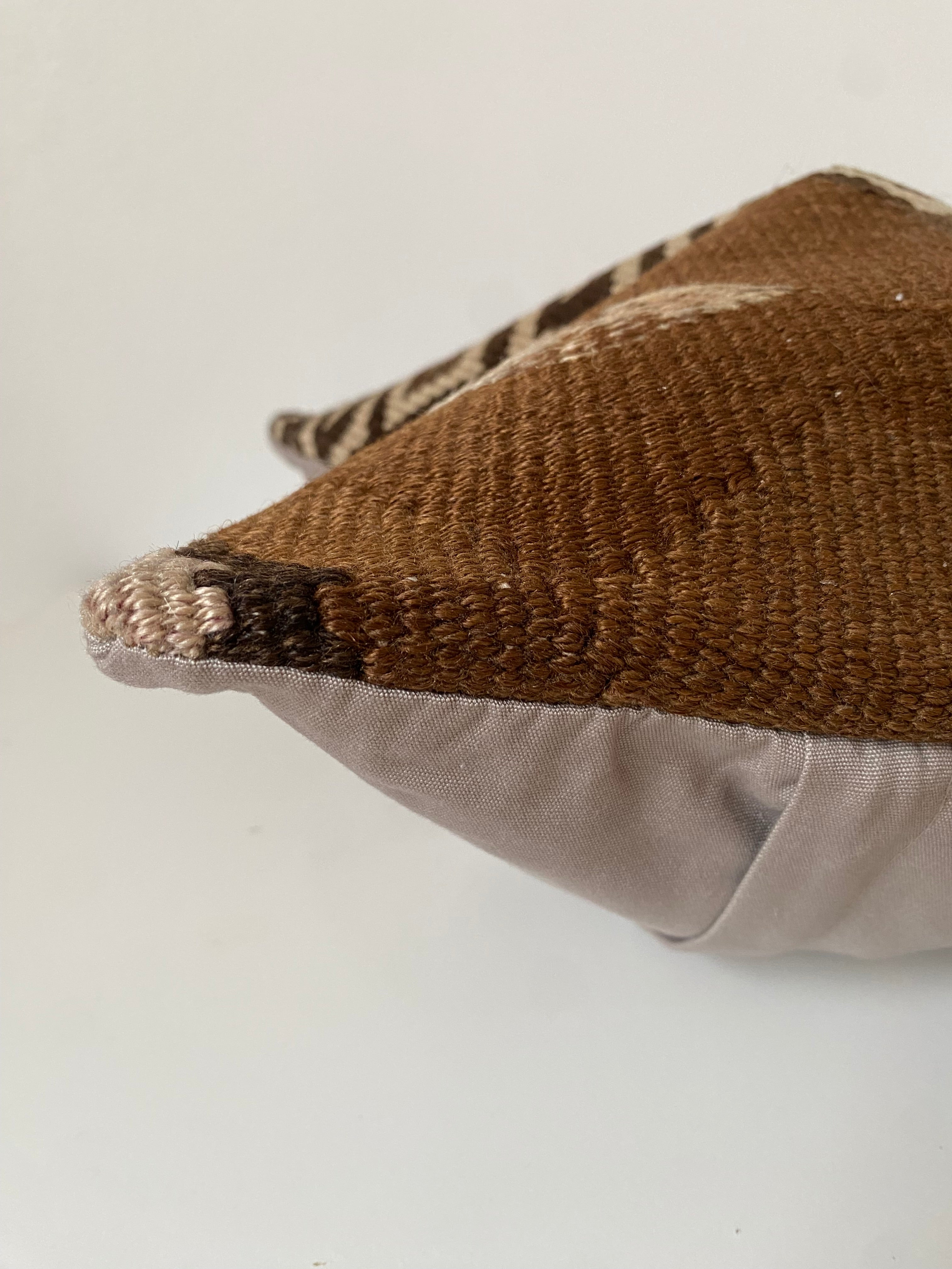 Close-up of a Turkish kilim textured pillow cover with a neutral colour palette on a white background