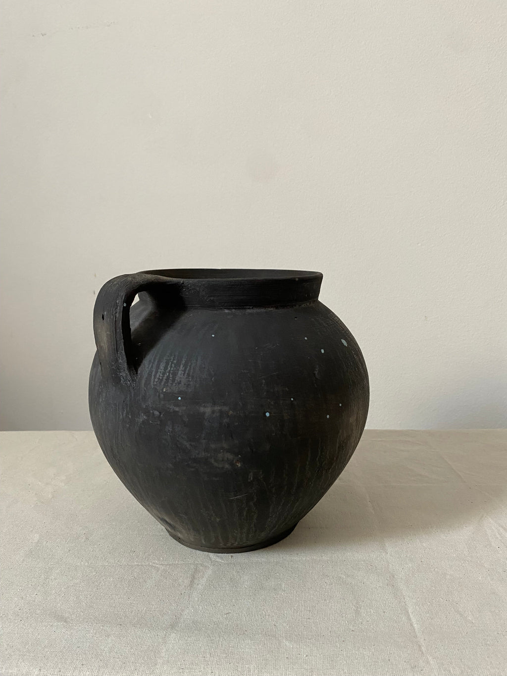 Black antique clay pot on a light gray background