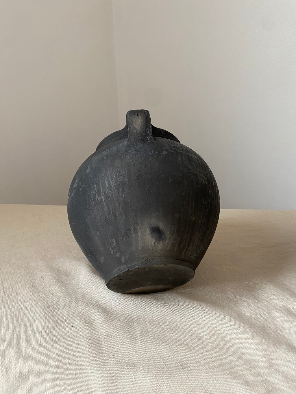 Black antique clay pot on a light wooden surface