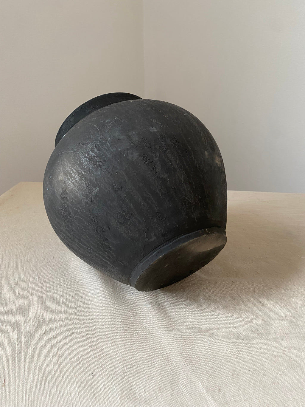Black antique clay pot on a light gray surface