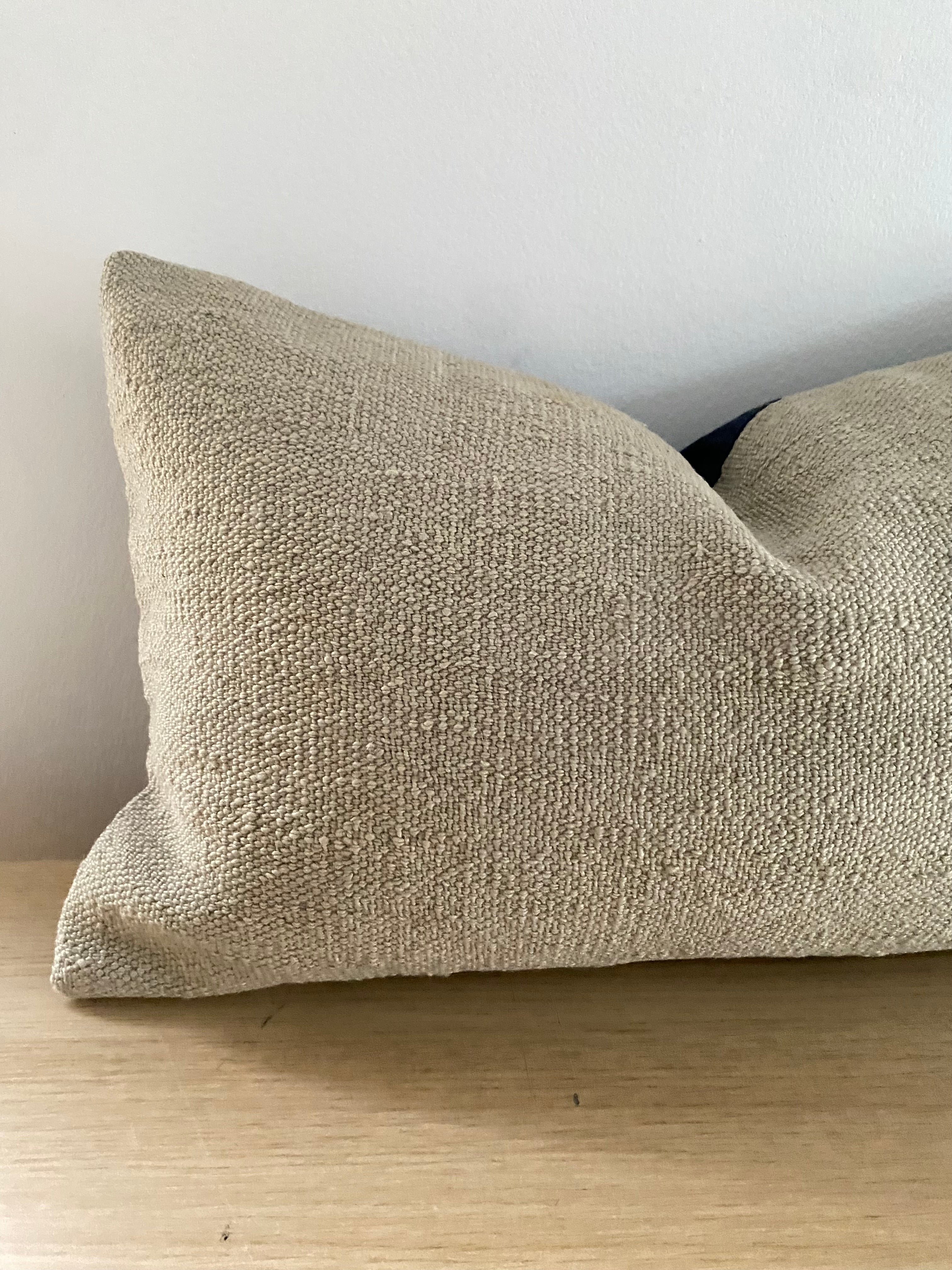 Turkish Kilim Lumbar Textured beige pillow cover on a wooden surface with a neutral backgrounds 