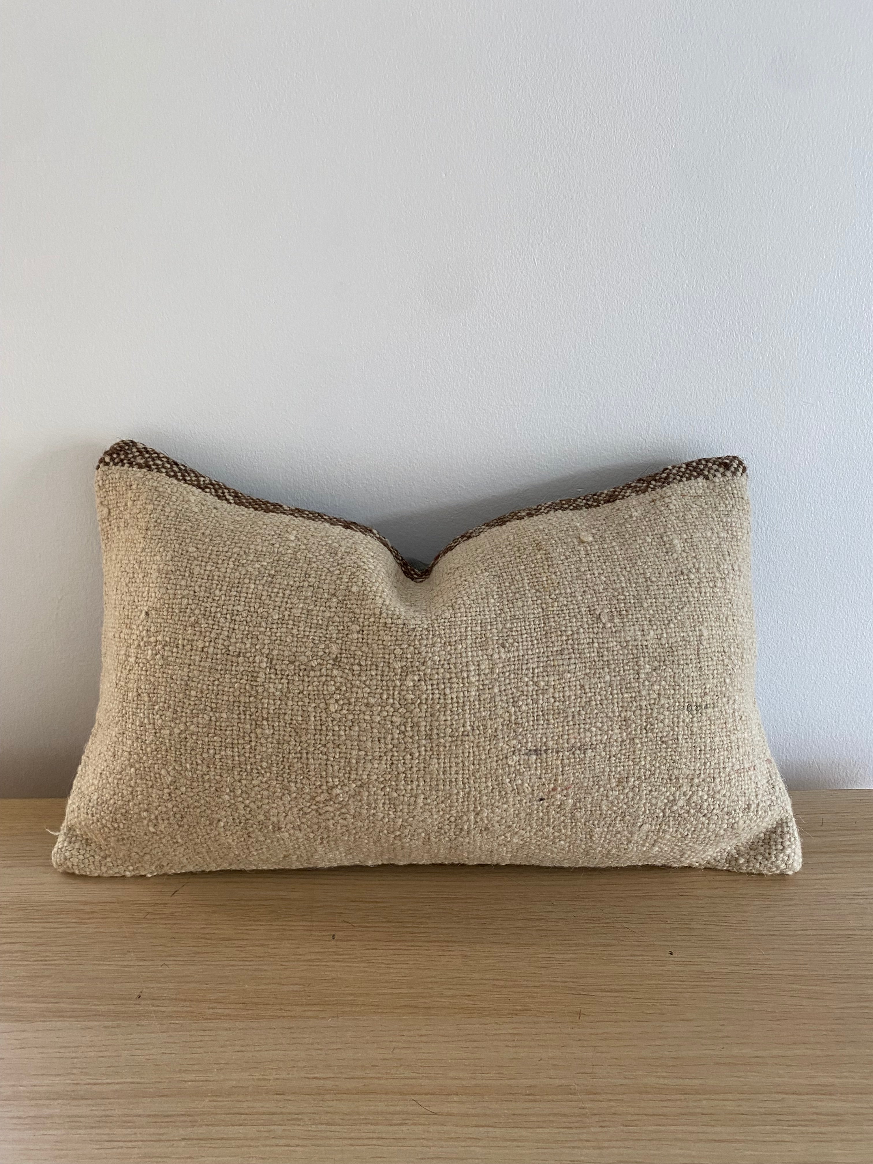 Turkish Kilim Lumbar Pillow Cover Textured beige pillow on a light wooden surface