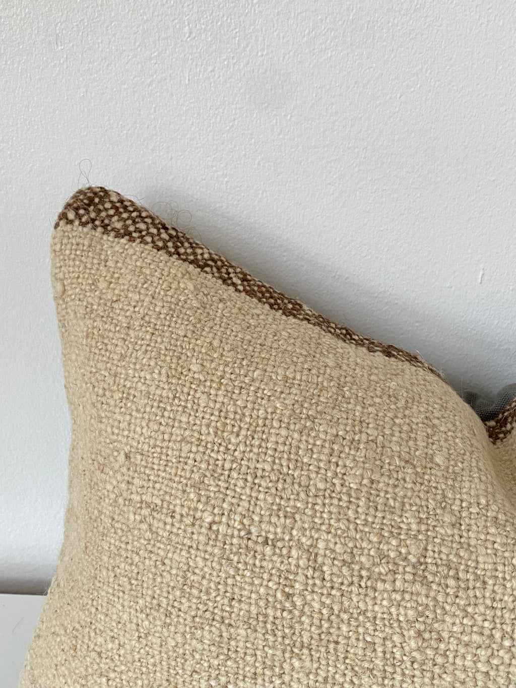 Textured Beige Turkish pillow cover with brown trim on a light grey background