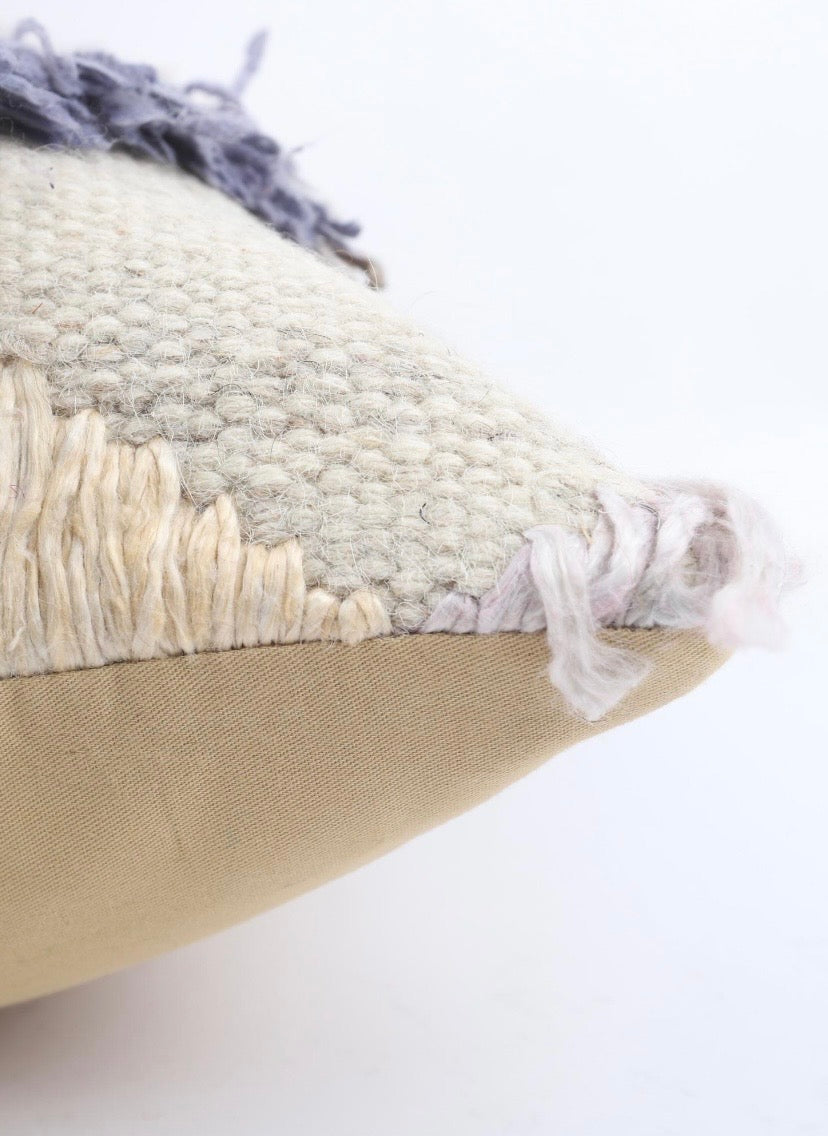 A close-up of a decorative Turkish Kilim Pillow Cover showing its mixed textures, including a woven cream and grey top section with frayed tassels and a smooth beige bottom section.
