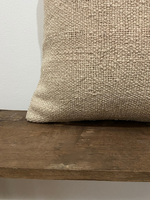 Textured beige Turkish Kilim pillow cover on a wooden surface with a neutral background