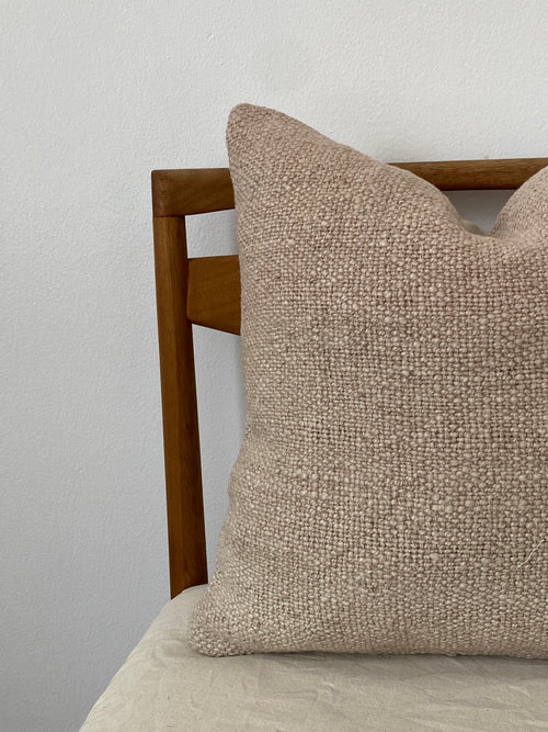 Textured Turkish Kilim pillow cover on wooden chair on a light background