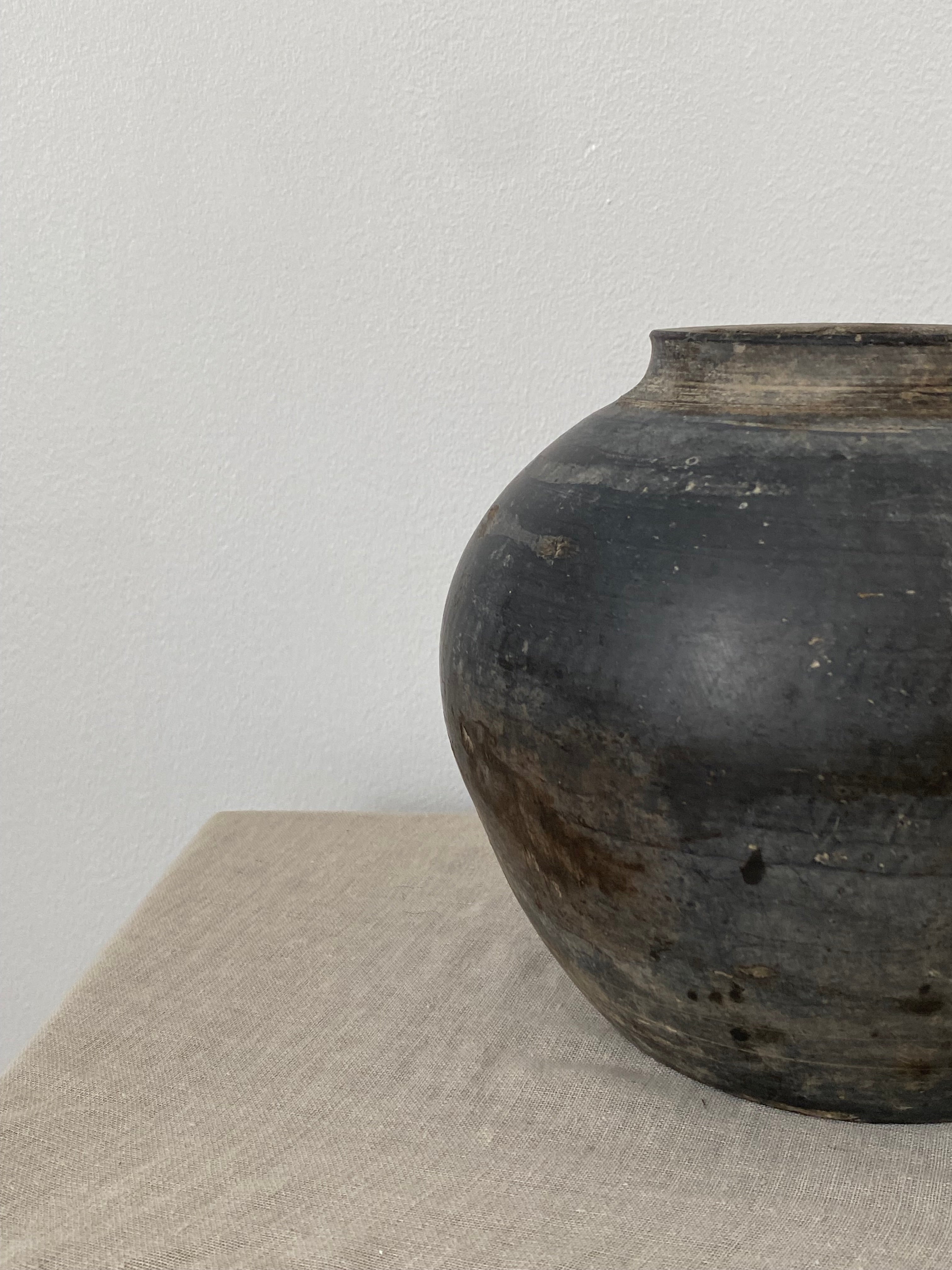 Black antique clay vessel on a light gray background