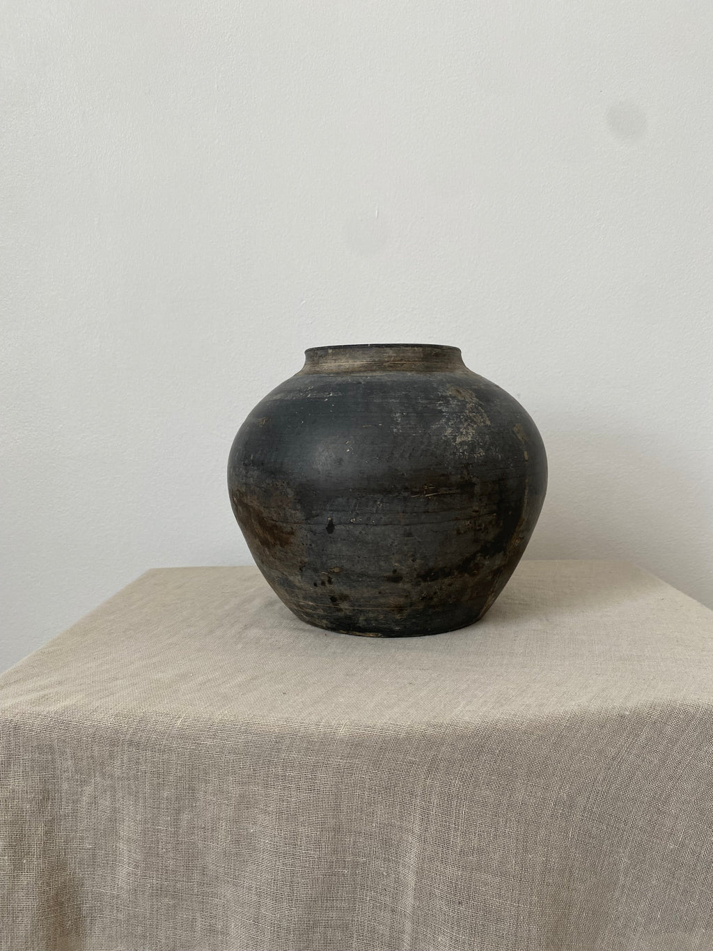 Dark Grey clay pot on a light gray surface with a white background
