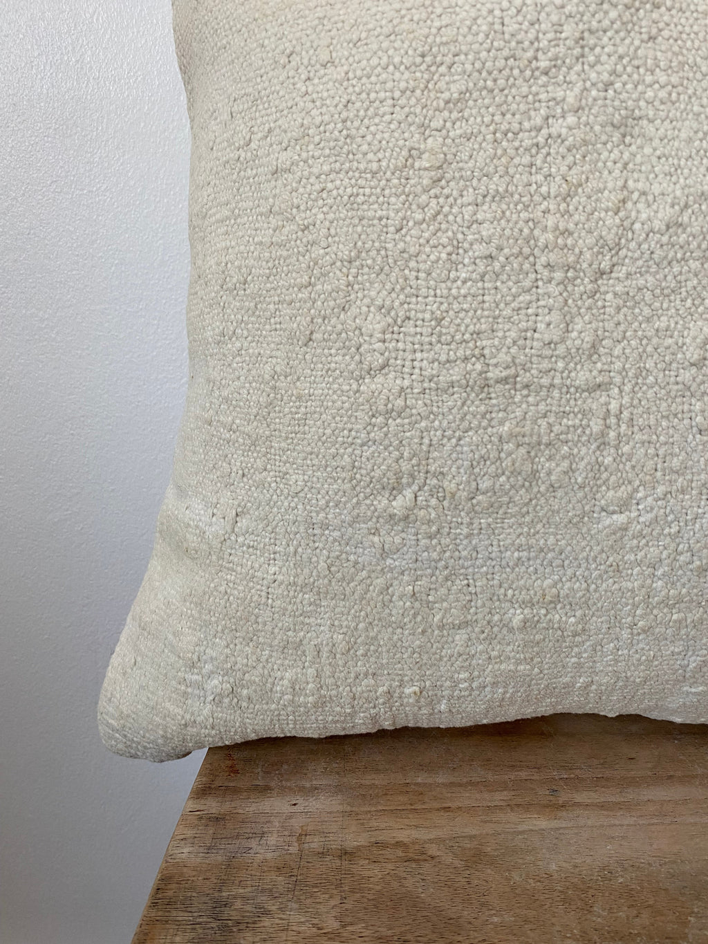 Textured off white pillow cover on a wooden stool
